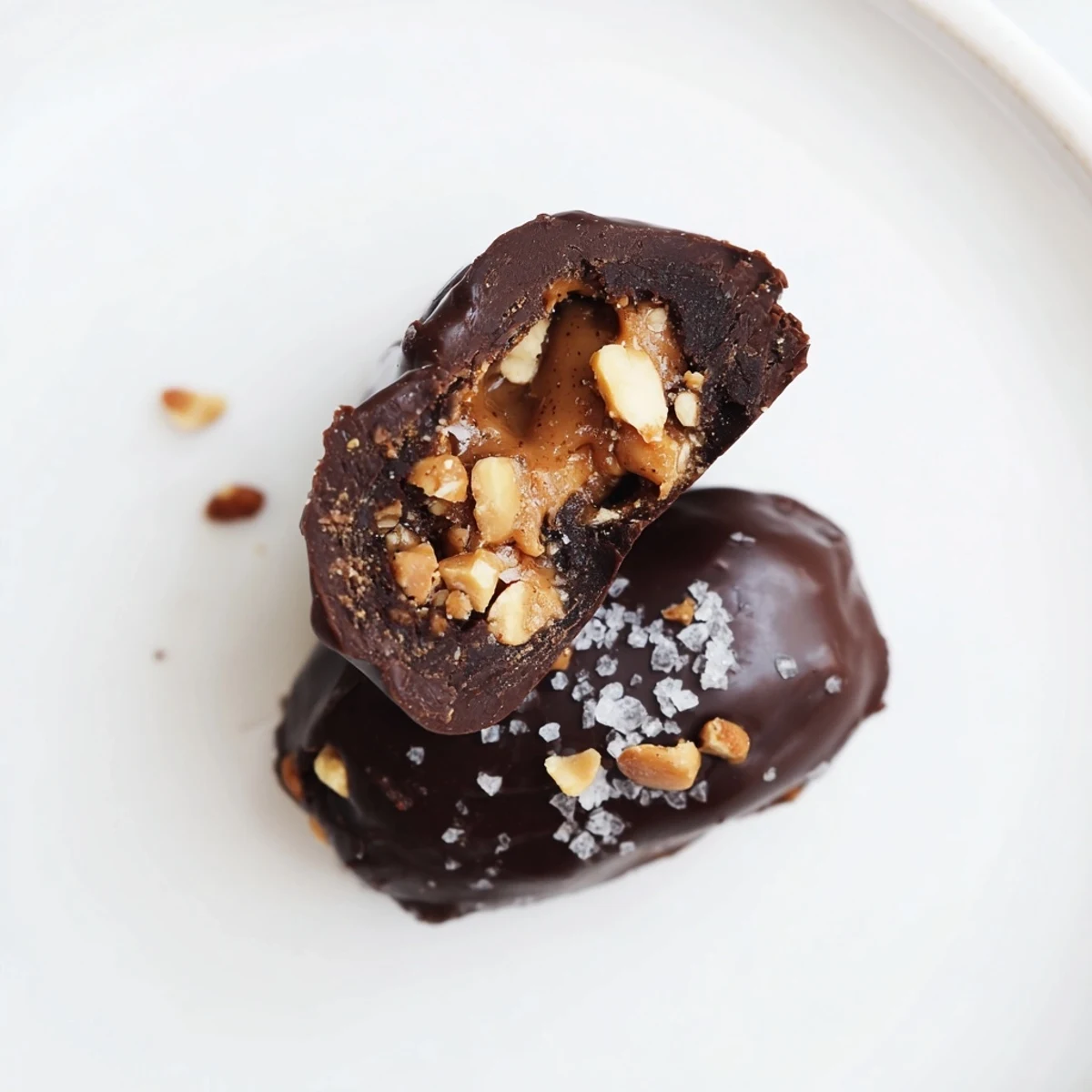 Chocolate-dipped Date Snickers sprinkled with flaky sea salt on parchment paper