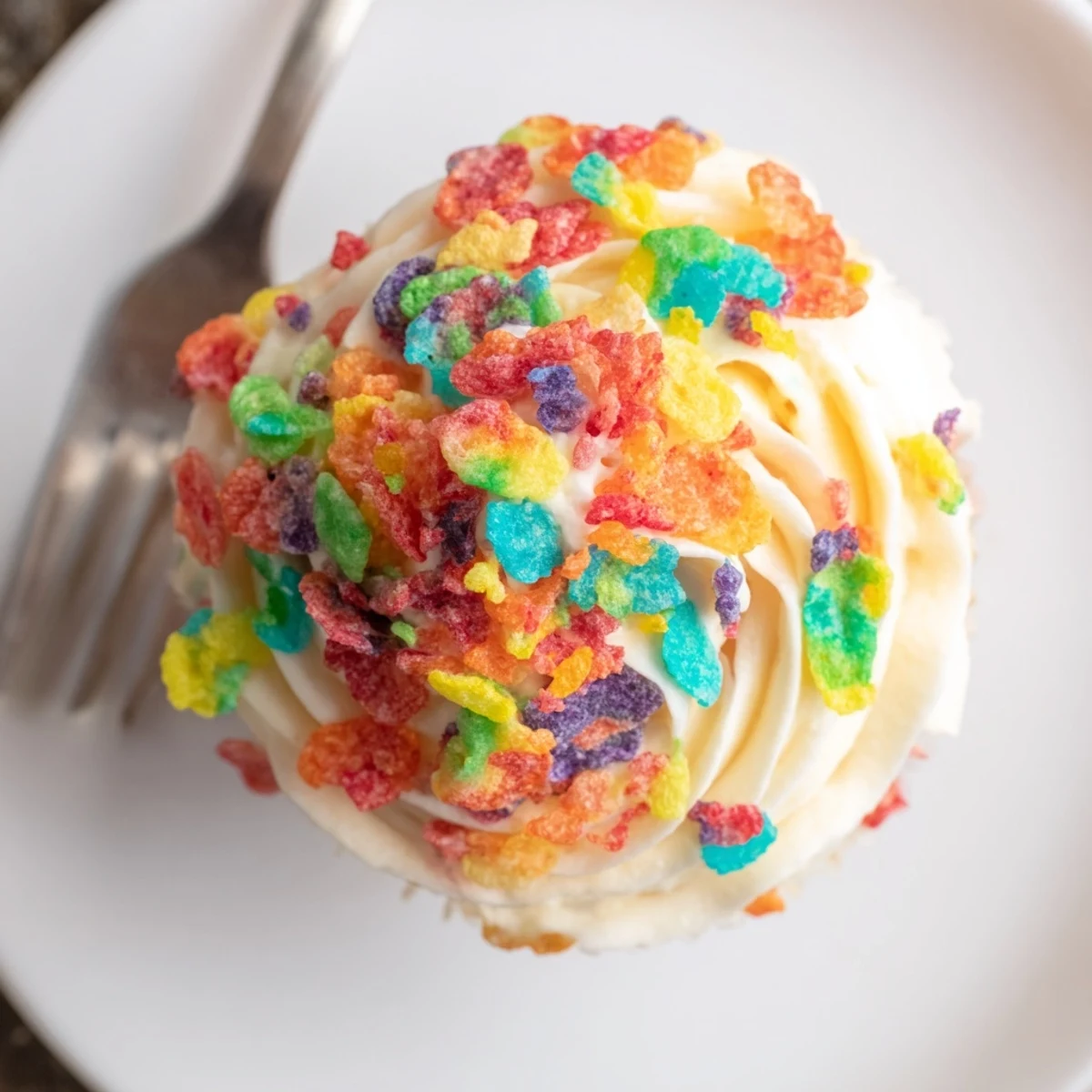 Fluffy pink frosting swirled with crunchy colorful Fruity Pebbles cereal on desserts