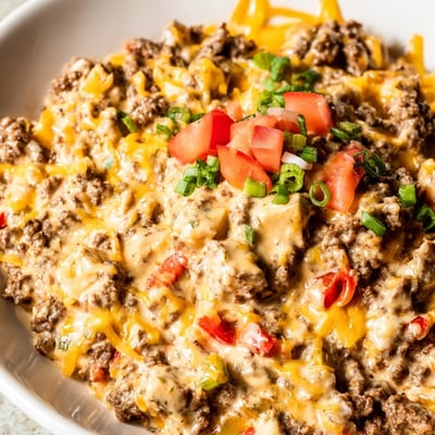 A skillet of melted Queso Dip with Ground Beef and Peppers, featuring colorful bell peppers and a rich, cheesy texture.