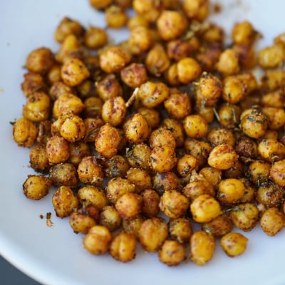 Cajun Spiced Roasted Chickpeas sit on a parchment-lined tray, glistening with spices and olive oil for easy snacking.