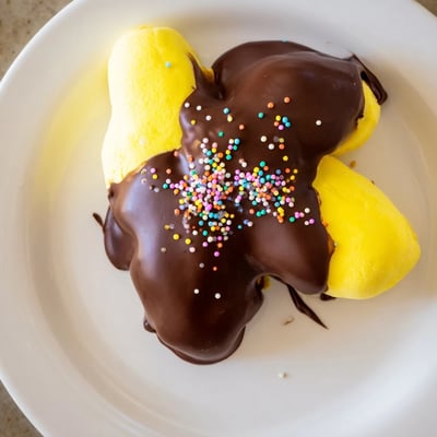 A close-up of chocolate covered Peeps on a baking sheet, perfectly dipped and decorated for Easter or spring celebrations.  