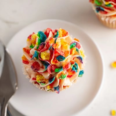 Smooth buttercream frosting studded with rainbow Fruity Pebbles on a frosted cake